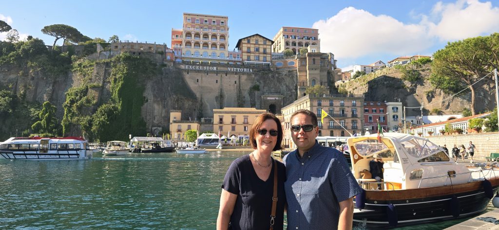 Sorrento marina couple posing by boats with cliffside Excelsior Vittoria hotel in the background