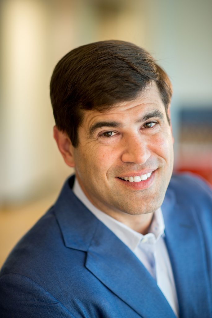 Smiling man in blue suit, professional business headshot close-up for LinkedIn or corporate bio